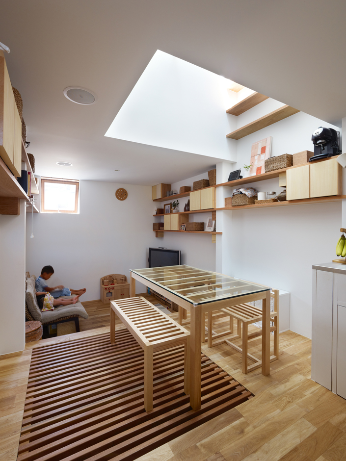 「六甲の狭小住宅2・神戸」キッチンからダイニング・リビングを見る。吹抜けの下にあるテーブルや椅子をスノコ状にすることで、太陽の光を1階まで届けることができる 設計／七島幸之　撮影／アトリエ・フロール