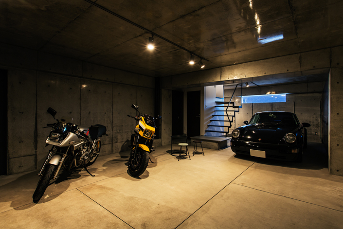「伏見のガレージハウス・京都」ガレージ内。ビルトインでクルマ2台、バイク複数台を格納できる。コンクリート打ち放しのハードなイメージ