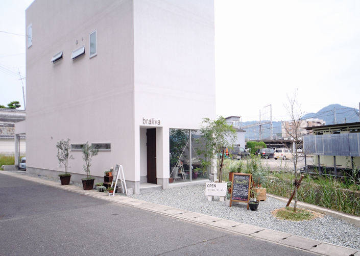 「五位堂の店舗併用住宅（カフェ)・奈良」外観を見る。四角いハコを置いたようなシンプルなデザインの外観。1階の茶色のドアが店舗出入り口。