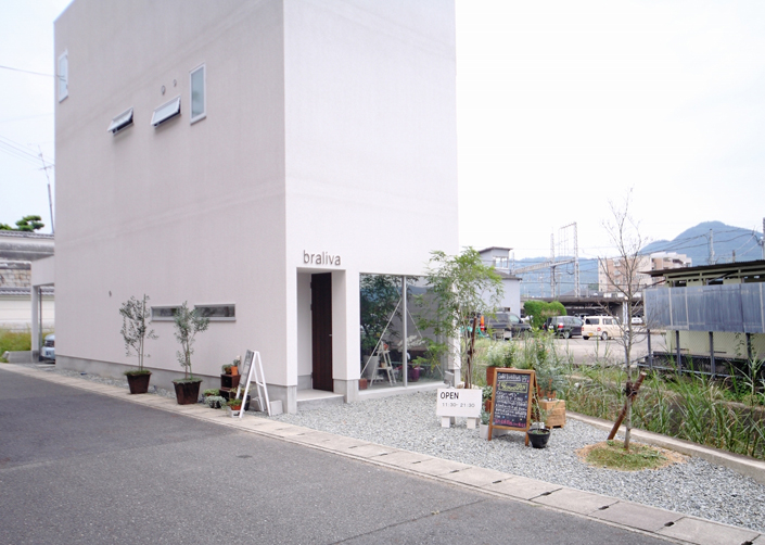 「五位堂の店舗併用住宅(カフェ)・奈良」外観を見る。四角いハコを置いたようなシンプルなデザインの外観。1階の茶色のドアが店舗出入り口。