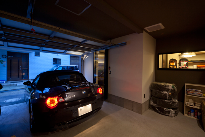 「昭島のガレージハウス」ガレージ内を見る。クルマ2台を並列に駐車できる。右奥は、ガレージ内を眺められる書斎