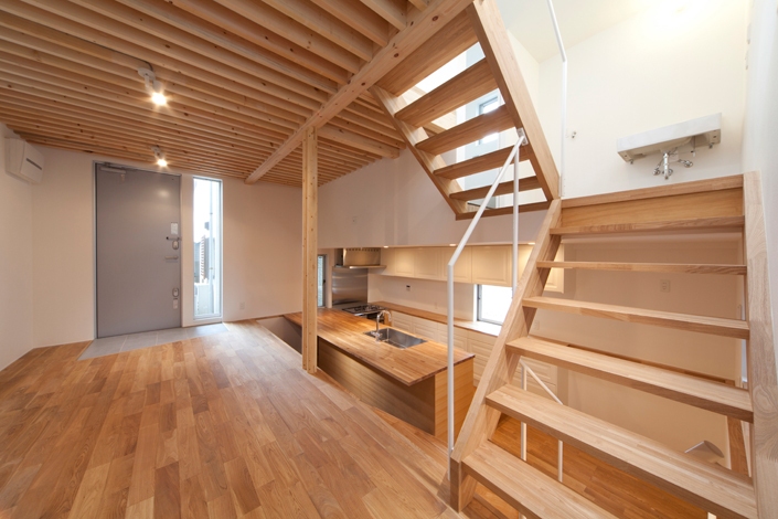 「祖師谷大藏の狭小住宅・東京(建築面積 約8.3坪)」1階LDKを見る。来客が多く、料理でもてなしするのた、カウンター式のキッチンを半地下に設けて、お店のような雰囲気に。