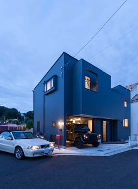 「町田のガレージハウス・神奈川」外観夜景を見る。黒いガルバリウム鋼板を採用し、耐久性とデザイン性を高めてている