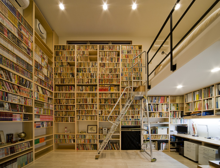 「本駒込の家・東京」地下にある書斎。吹抜けスペースを活かした本棚。およそ3,000冊が収納できる。中央には備え付けのデスク。手前には打ち合わせスペースもある。ロフト部分にはベッドが置かれ、ご主人の寝室となっている。設計／金 富雄＋李 勝代