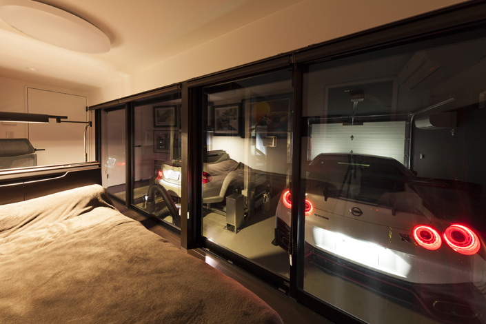 「神奈川のガレージハウス」1F寝室を見る。ガレージとの間をガラスにすることで、建築主の要望だった「クルマと寝る」ことを限りなく実現している。　設計／建築家 濱里豊和　撮影／アトリエ・フロール株式会社
