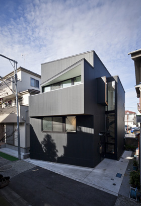 「下丸子の狭小住宅・東京」黒いガルバリウム鋼板に覆われた外観。斜めになった軒や凹凸のあるカタチは、一度縮まったモノが広がろうとする動きを表現している