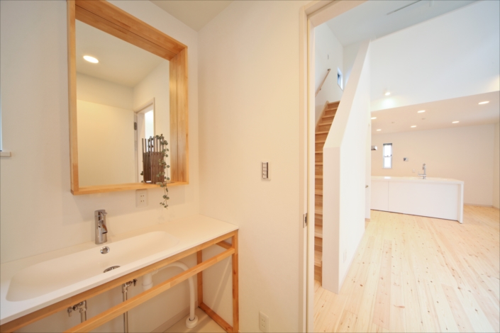 「東綾瀬の狭小住宅・東京(建築面積 約11.7坪)」洗面スペースからLDKを見る。本物の木材が出すナチュラルな雰囲気。白を基調としているので、狭いスペースでも明るく開放感がある