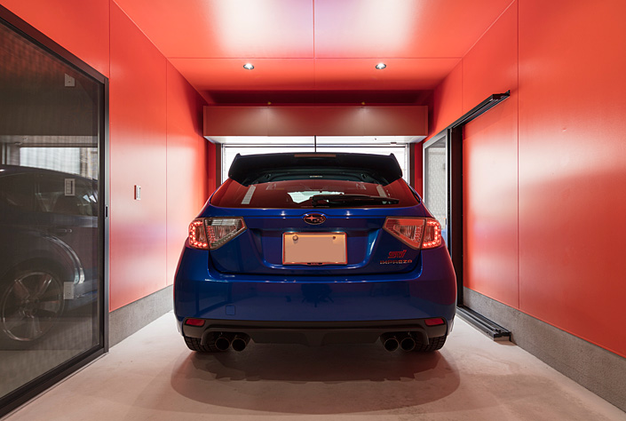 「神楽坂のガレージハウス・東京」 オレンジ色の壁が車体のブルーに深みを与えている。 ガレージには空調を付けた趣味部屋もあり、ガレージライフを充実したものに。設計／濱里豊和